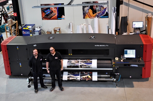 Manager Johan Ceuleers and large format print operator Jasper Corne, in front of the EFI VUTEk® GS3250LXr Pro roll-to-roll printer